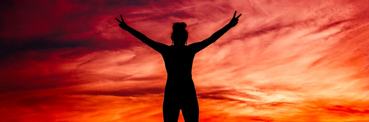 How to Be Brave When You Have Mental Illness A person standing on a mountain looking at a sunset