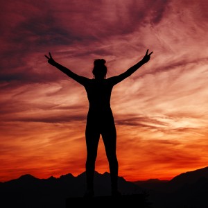 A person standing on a mountain looking at a sunset