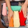 Hands placing folded clothes into suitcase