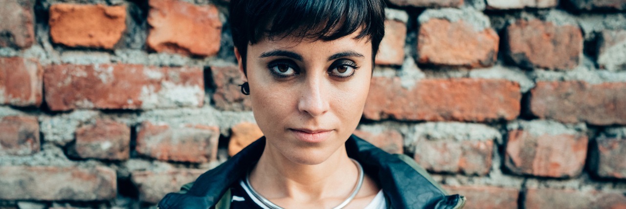 6 Things I Wish My Healthy Friends Understood About My Illness Woman standing in front of a brick wall.