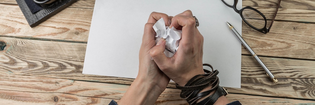 The Anxiety and Frustration at Not Being Able to Function Hands crumbling up a piece of paper, sitting at a desk with a type writer