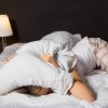 Woman hiding under pillow in bed