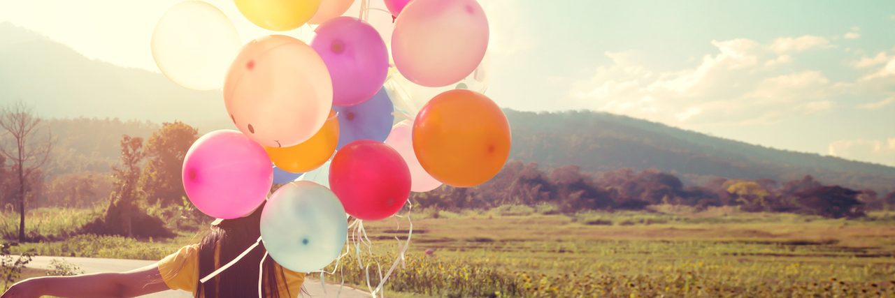 Woman walking down the road holding a balloon