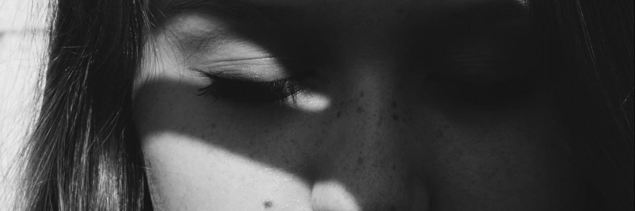 Happiness Is Not Always a 'Choice' When You Have Depression Dramatic artistic portrait of an attractive long haired young woman with downcast eyes and a serious expression casting a dark shadow silhouette of splayed fingers across her face in the sunshine