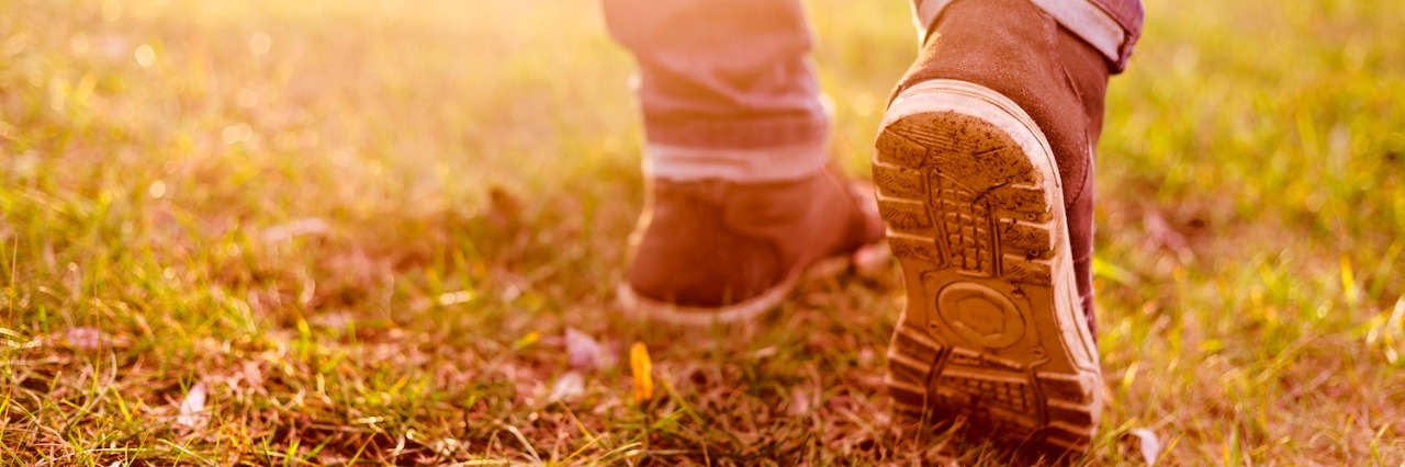 Leaving My Comfort Zone as an Autistic Person Close-up of person's legs and shoes walking on muddy grass
