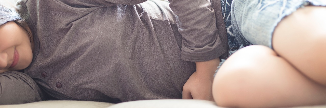 The Unexpected Physical Effects of Anxiety woman with stomach cramps on sofa