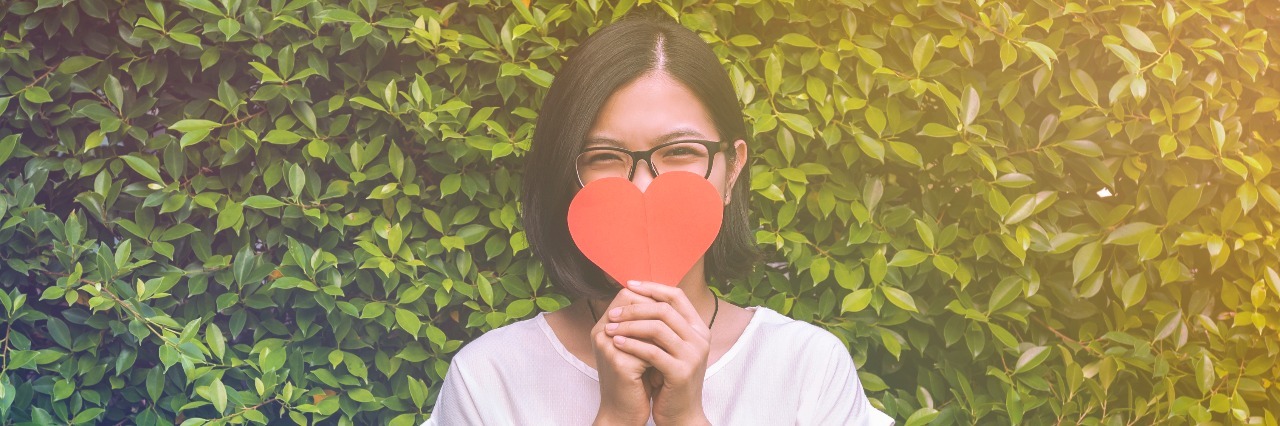 girl with eye glasses, take a heart and plants background for Valentines day, soft focus.