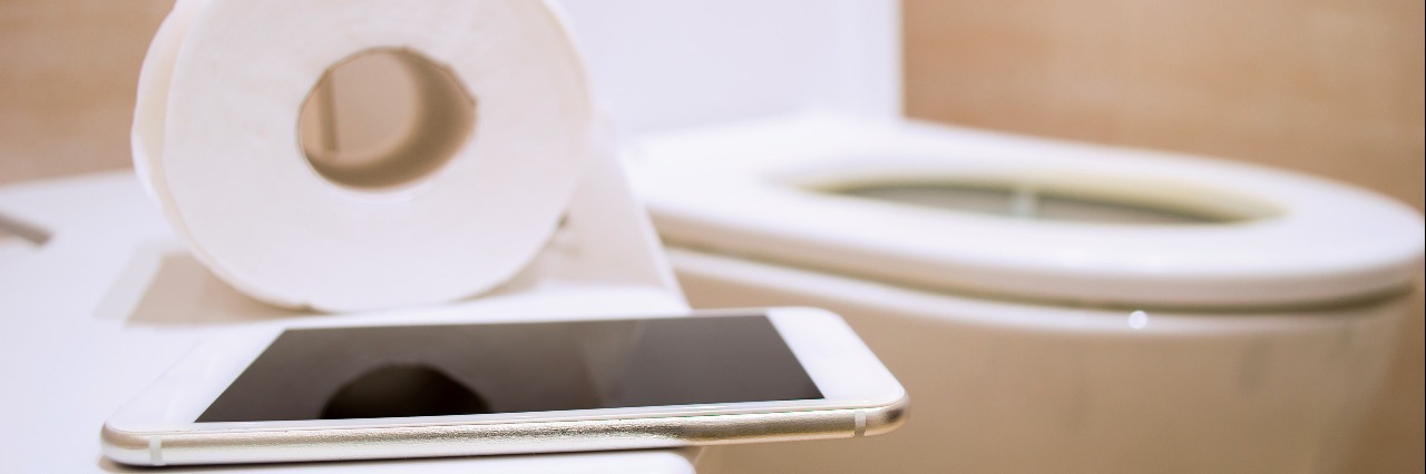 Dear Bathroom Reader: A Letter To Myself During a Crohn's Flare close up of toilet paper and a phone