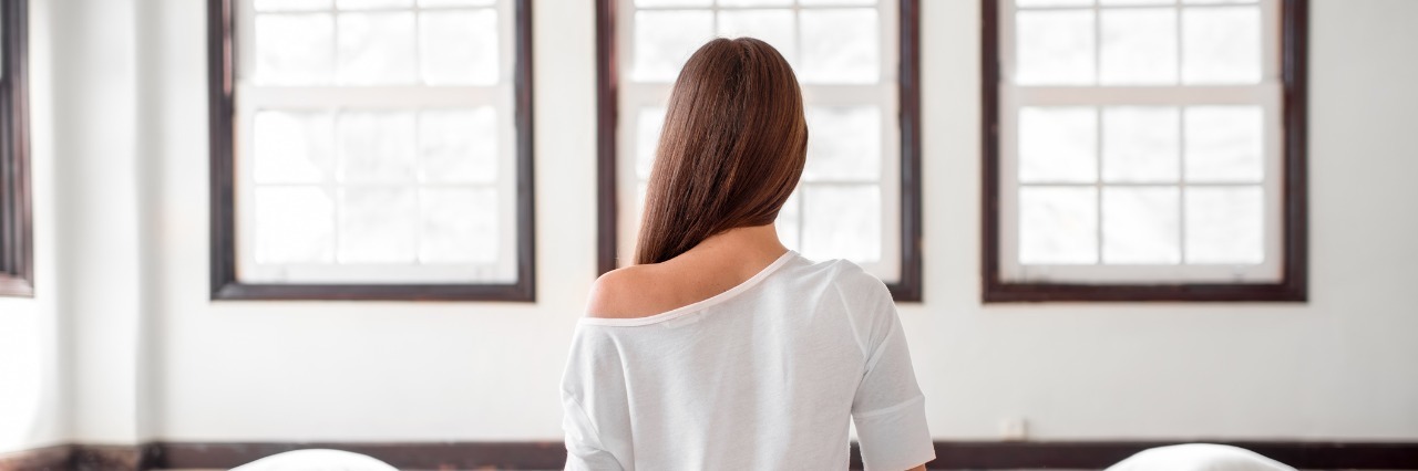 Chronic Illness: Choosing Health Over Dreams woman sitting cross-legged on the floor looking out the window