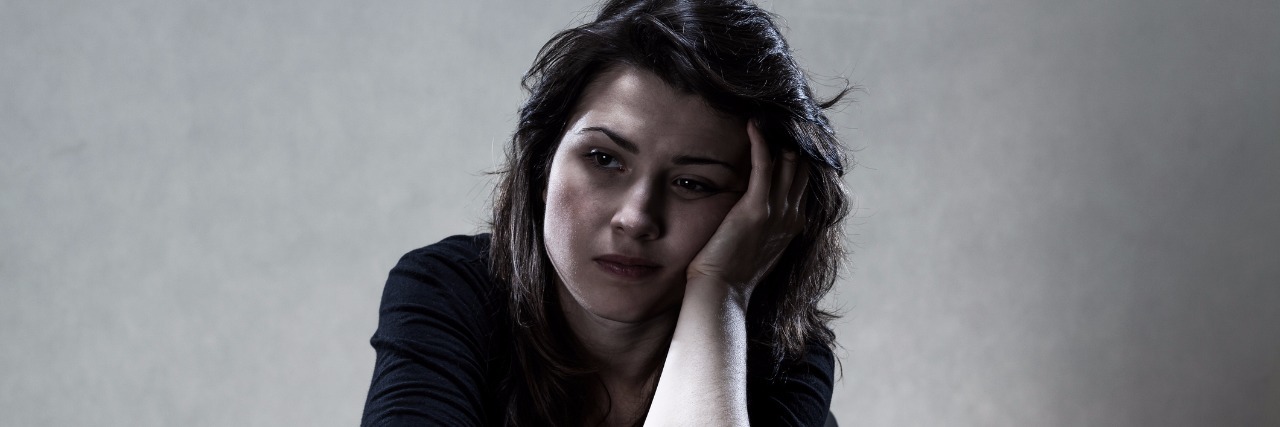 How Trying to Be a Good Patient Has Made Me a Terrible One sad woman with head on hand sitting at table