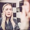 woman looking at herself in the mirror with her hands on her cheeks