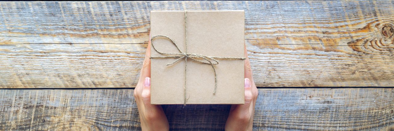 Best Gifts to Give Someone in Eating Disorder Recovery Womans hand holding craft gift box on wooden table close up