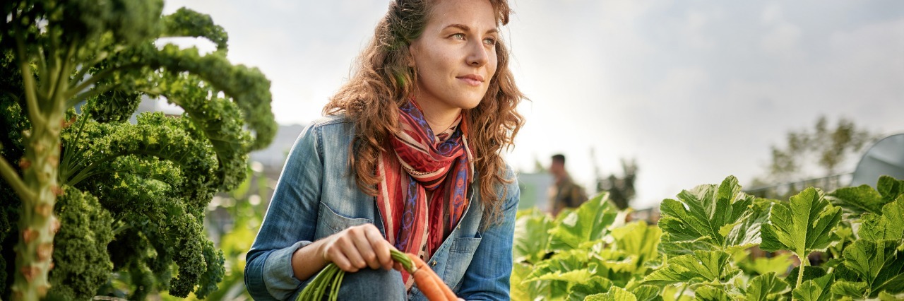 Lupus: How Nature is an Encouraging and Restorative Force in Illness woman holding carrots and working in her garden