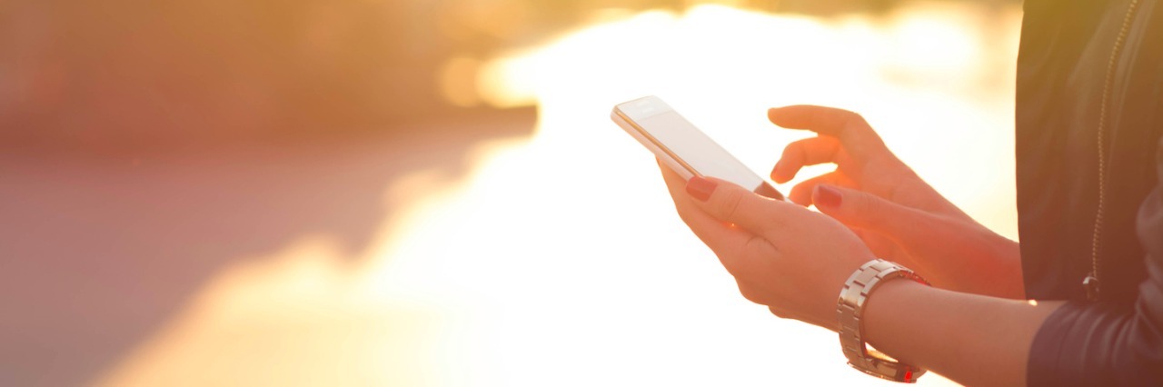 How Communication Can Be Hard for Me as an Autistic Person Woman holding cell phone while outdoors