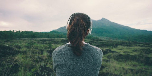 Back view of woman wearing headphones listening to music in nature