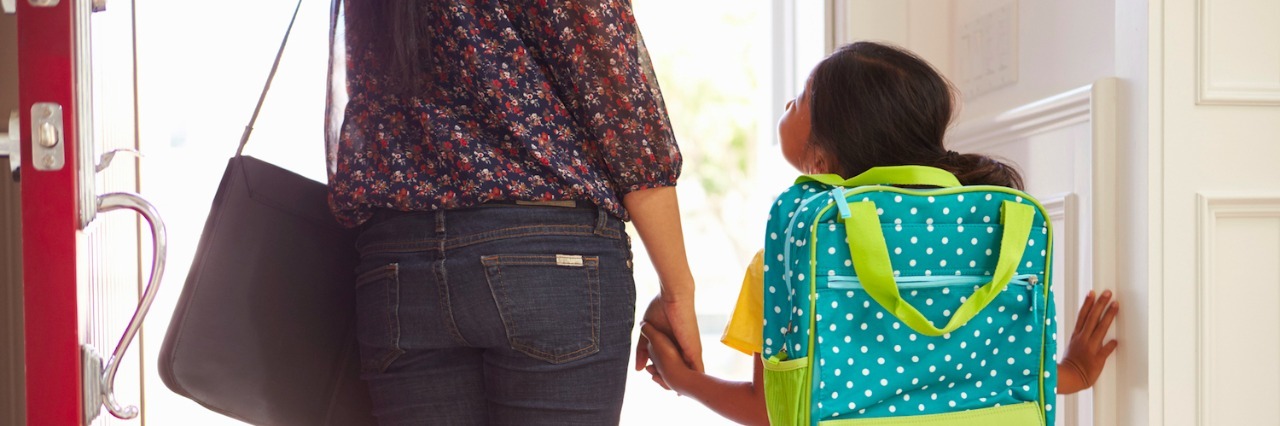Mother and daughter holding hands, walking out door of home on the way to school
