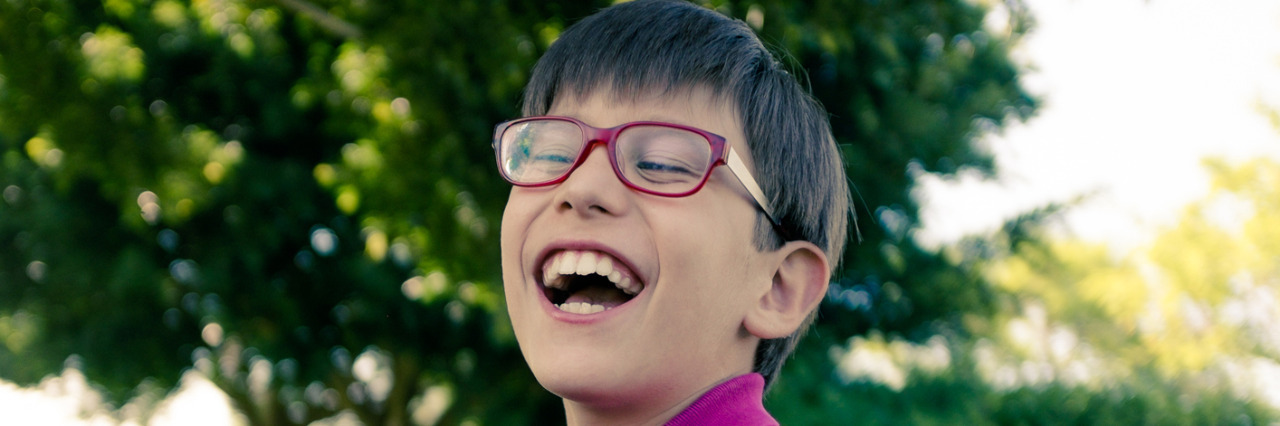 Happy boy with cerebral palsy sitting outside.