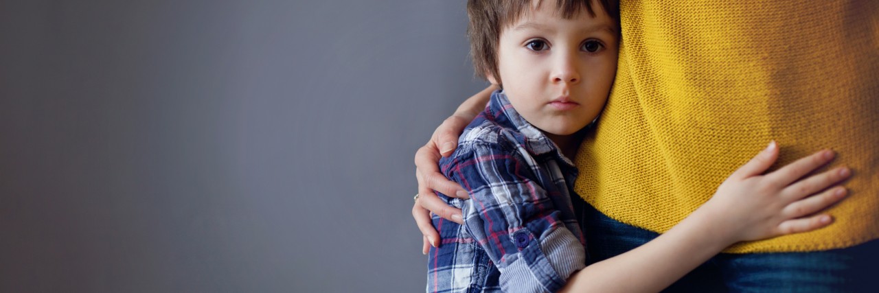 Sad little child, boy, hugging his mother at home