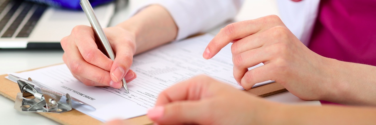 Doctors: Please Treat My Lyme Symptoms, Not the Test Results Female doctor hand hold silver pen filling patient history list at clipboard pad.
