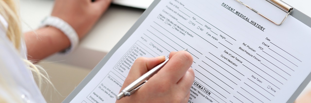 Finding Comfort in Receiving Diagnoses, Labels for Illness doctor holding pen and writing on patient medical record on a clipboard
