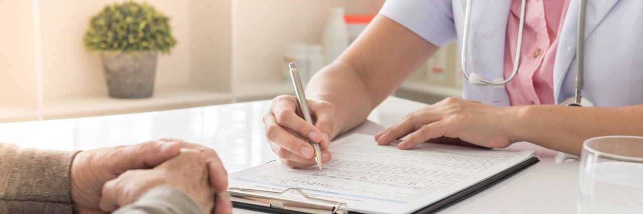 Benefits of Seeing Doctors Unfamiliar With POTS doctor writing notes while sitting at a table and talking with a patient