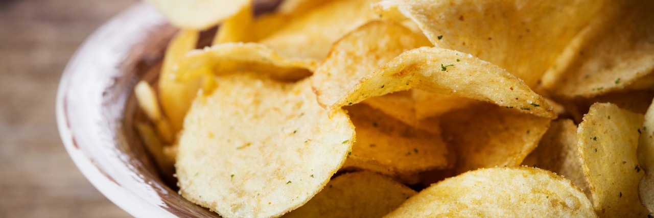 heap of potato chips in bowl on wooden background