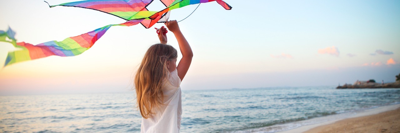 What I Wish I Knew After My Hypermobile Ehlers-Danlos Diagnosis young girl holding a kite and running along the beach