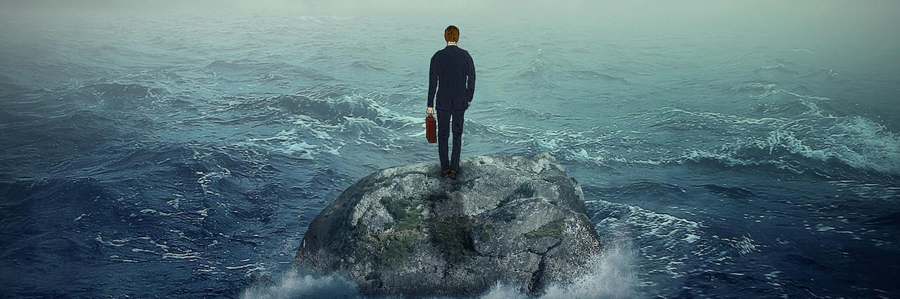 A man standing on a rock in the ocean