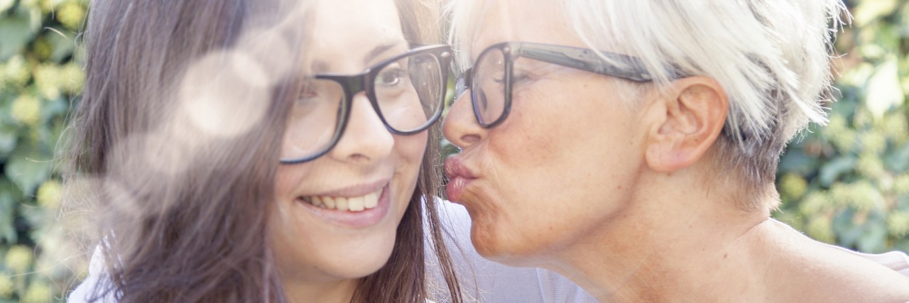 mother and adult daughter hugging each and having breakfast outdoors