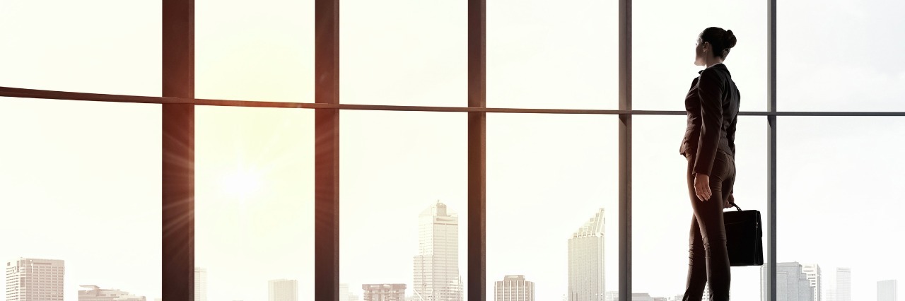 Should I Change Jobs if It Is Affecting My Mental Health Back view of businesswoman against panoramic office window. Mixed media