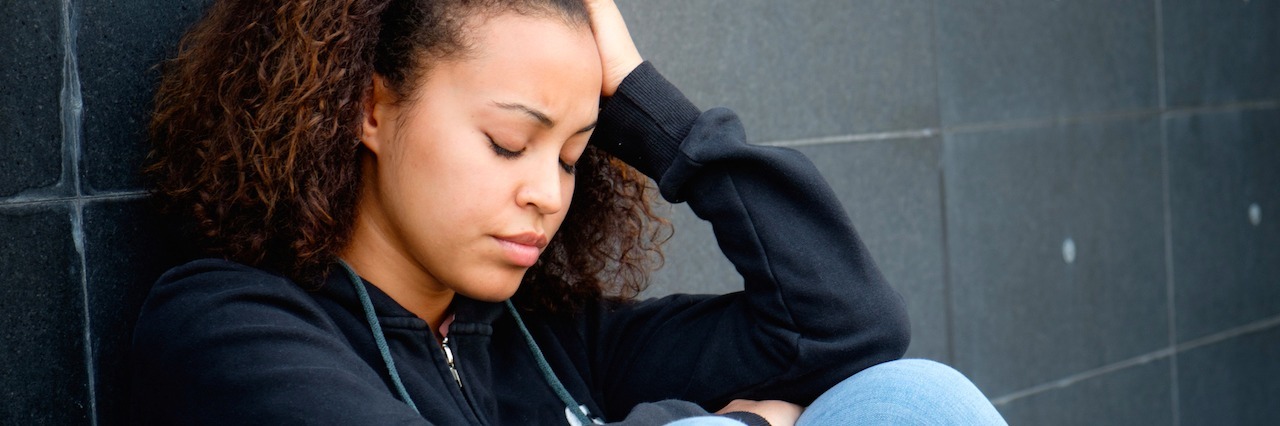 When Your Mental Illness Makes You Stand Out for the Wrong Reasons a woman sitting on the floor, looking sad