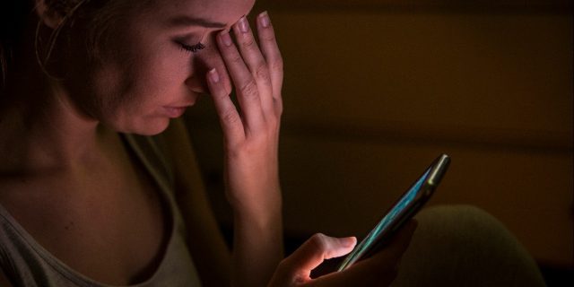 Upset woman using phone at night