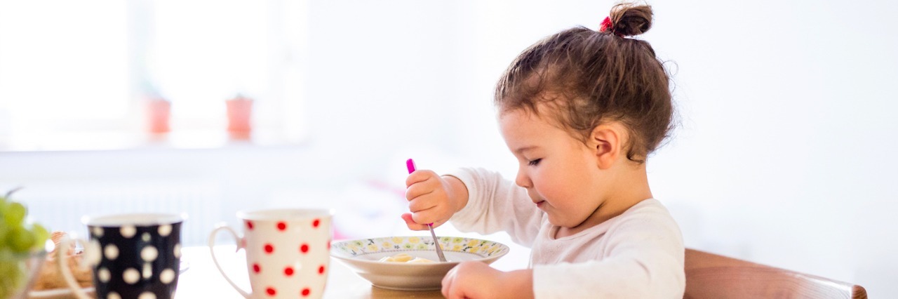 It's Not 'Picky Eating': 5 Strategies for Sensory Food Sensitivities Girl sitting at table in kitchen, eating breakfast