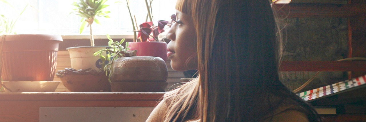 4 Things I’ve Learned About My Anxiety Disorder Woman sitting in cafe, looking out window with plants on the windowsill