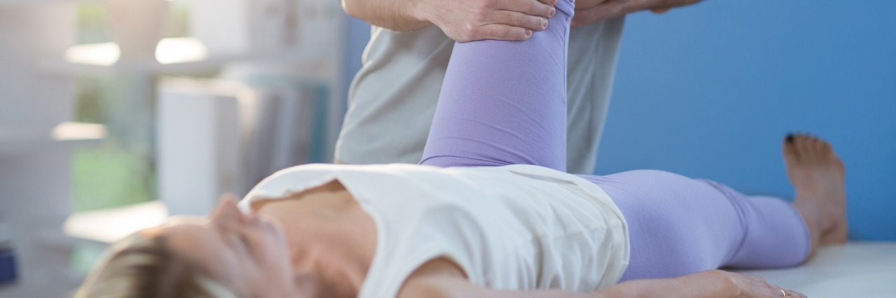 Fibromyalgia, Lupus: Physical Therapy and Chronic Pain Conditions male physical therapist helping a woman bend her knee in a clinic