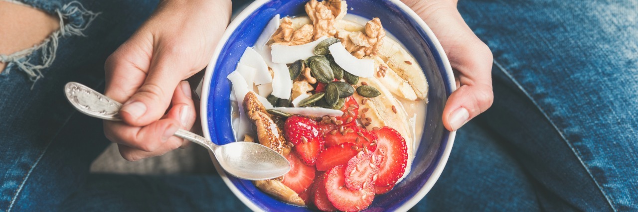 Sitting on ground, with bowl of good in a bowl.