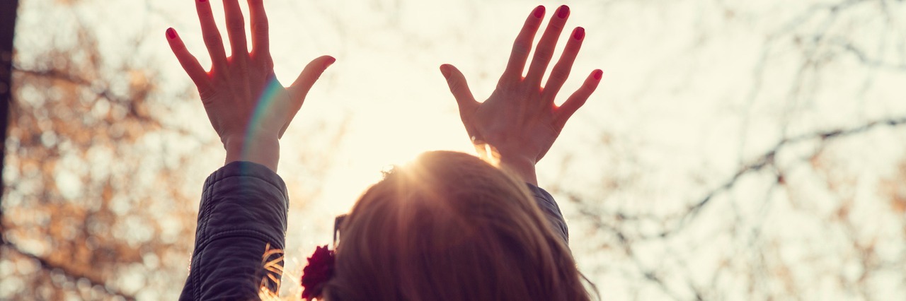 Important Lessons I Learned During Mental Illness Recovery A woman holding her hands in the air looking at a tree