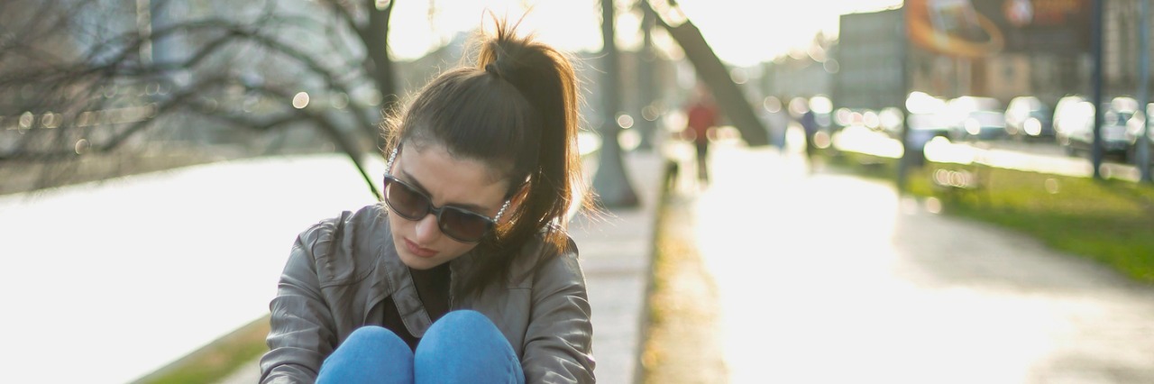 When You Feel Like You're 'Too Much' for Your Friends young woman sitting alone and sad, urban scene