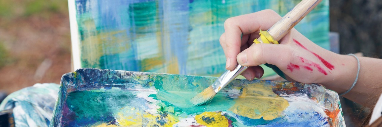 Fibromyalgia, ME: Using Arts Therapy, Creativity to Cope With Pain woman holding paint palette and painting on canvas