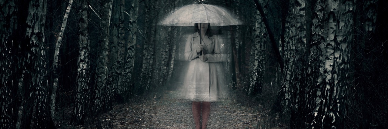 woman standing in woods holding umbrella