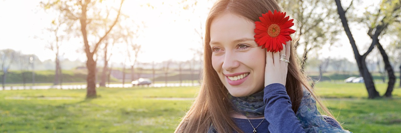 Chiari Malformation: Not Feeling Guilty for Being Chronically Ill woman smiling outside in a park with a red flower in her hair