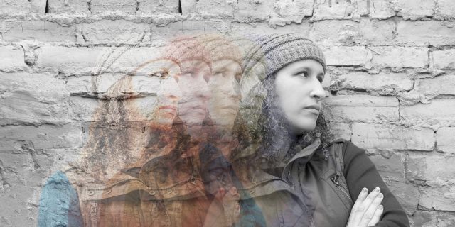 Multiple exposures of young woman standing with crossed arms against urban wall looking away