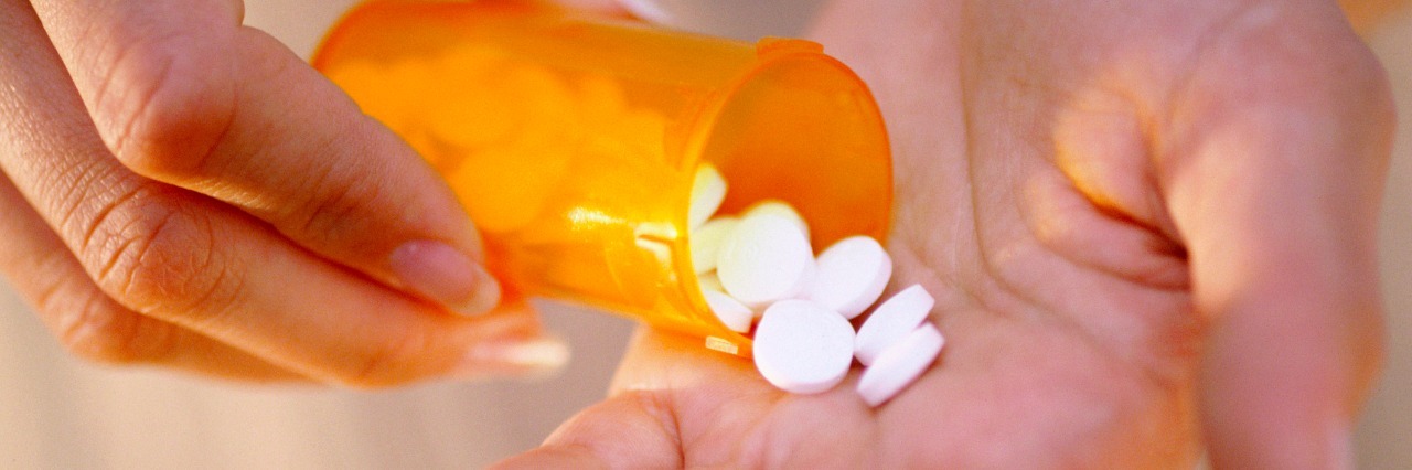 Close-up of a person's hand holding a bottle of pills