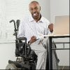 Businessman with cerebral palsy sitting in a wheelchair and working on a computer with his foot.