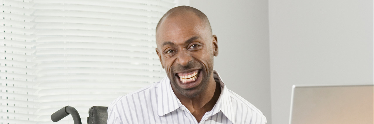 Fast Facts About Cerebral Palsy Businessman with cerebral palsy sitting in a wheelchair and working on a computer with his foot.