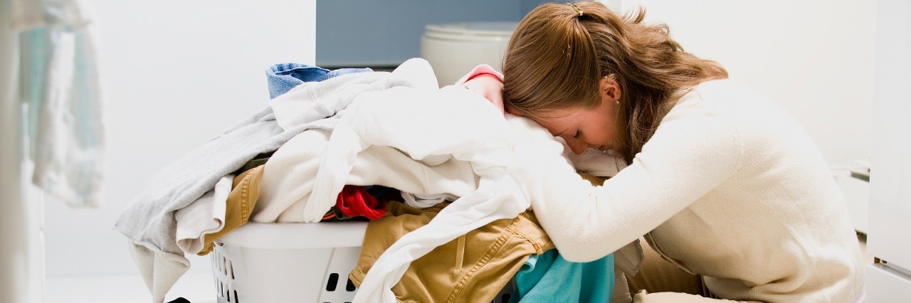 Exhausted woman sleeping by basket of laundry