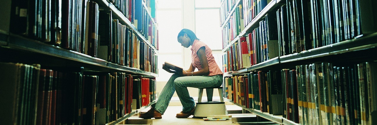 Female University Student Reading a Book in a Library