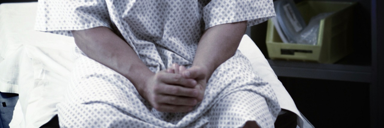 Man in hospital gown, sitting on hospital bed