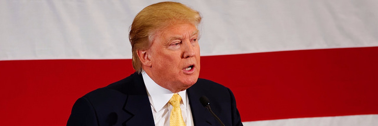 Trump Repeals Rule Blocking Those With Mental Illness From Buying Guns Donald Trump speaking in front of a flag background