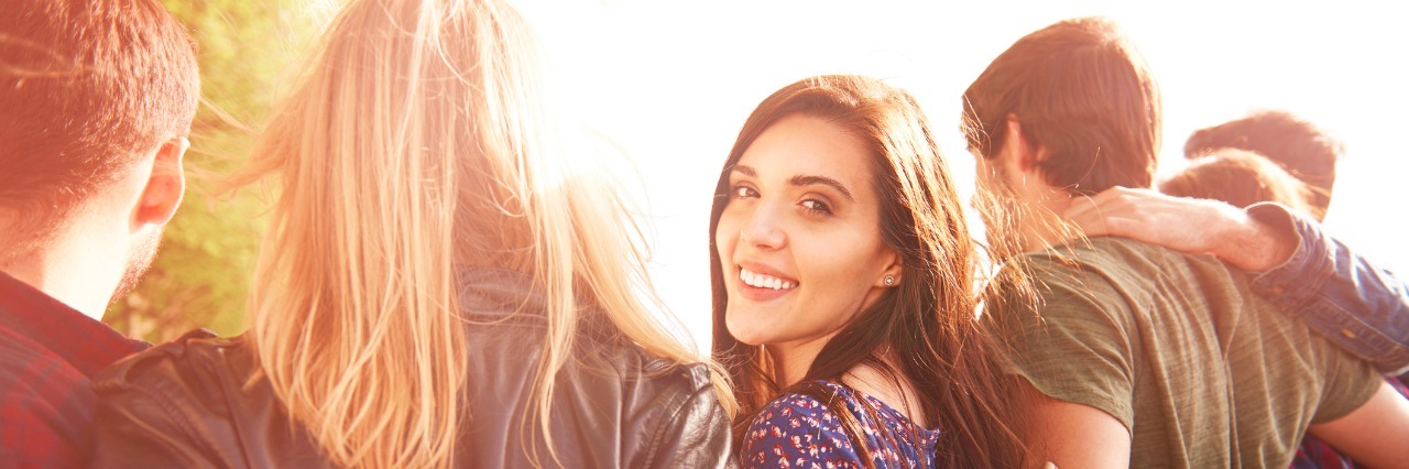 On Autism Acceptance and Awareness Month, Accept I Am Autistic group of friends hugging, one woman is turning back looking at the camera